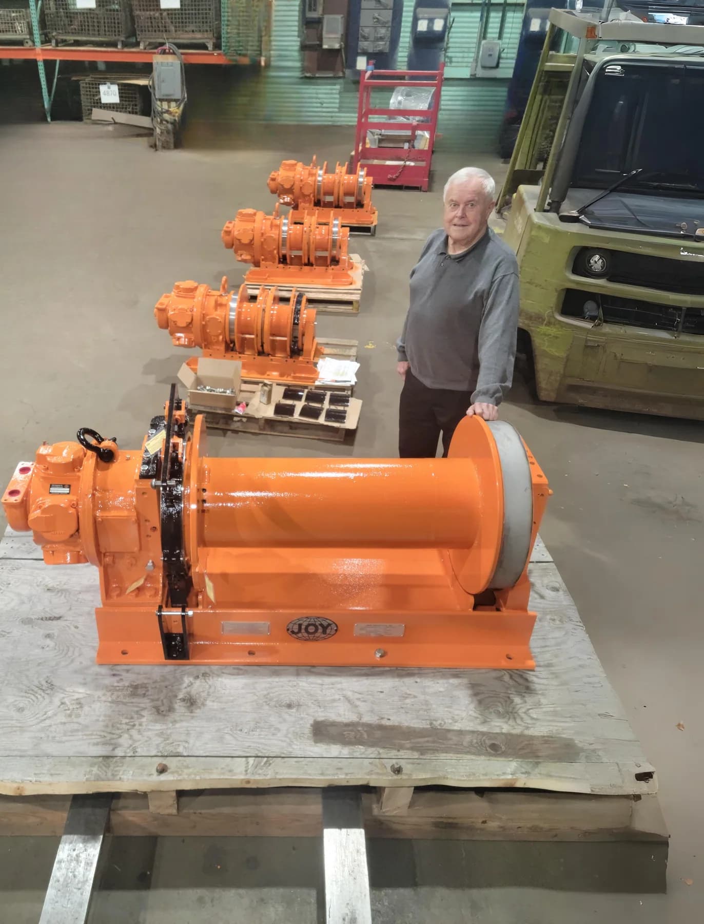 Row of orange JOY hoists on pallets, ready for shipment